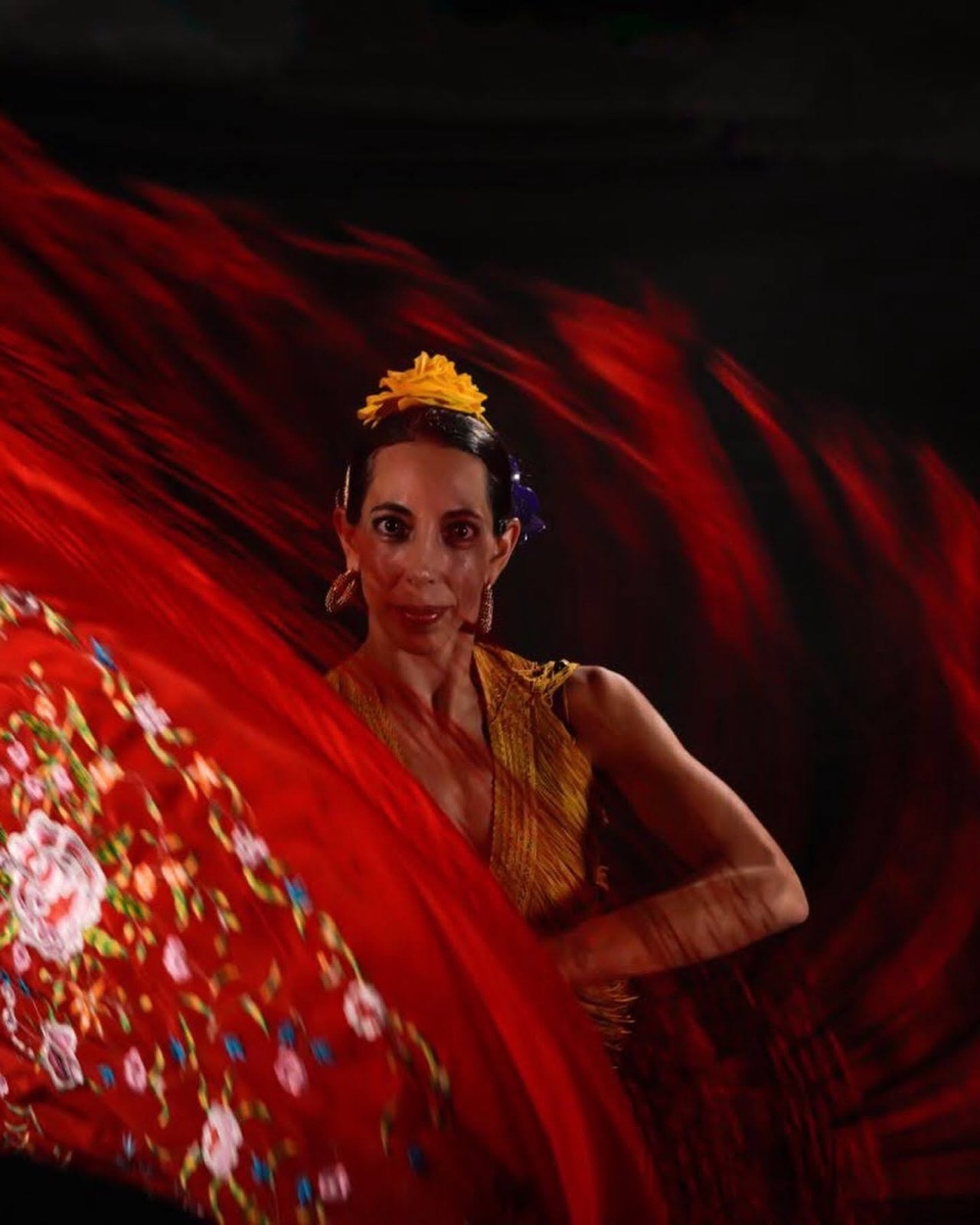 Bailaora de flamenco con mantón rojo en el escenario